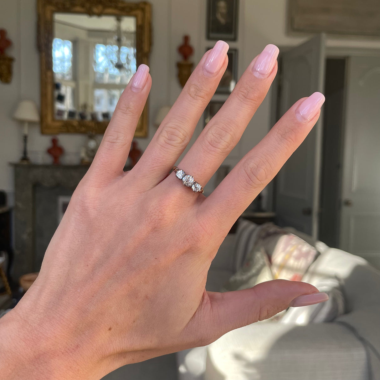 Antique Edwardian three-stone diamond engagement ring, worn on hand.
