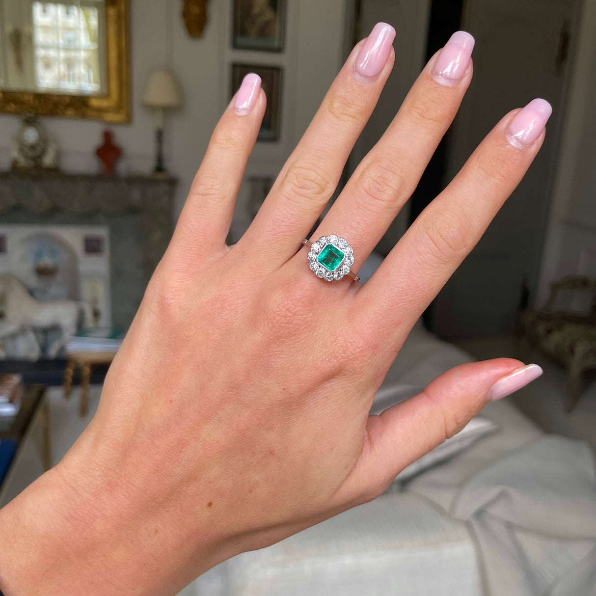 Edwardian emerald and diamond cluster ring, worn on hand.