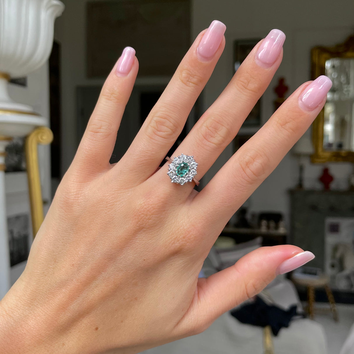 Austrian emerald and diamond cluster engagement ring, worn on hand.