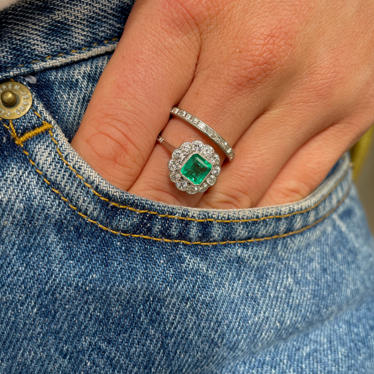 Edwardian emerald and diamond cluster ring, worn on hand.