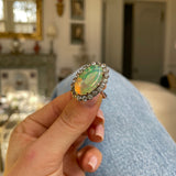 Antique opal and paste cluster ring, held in fingers.