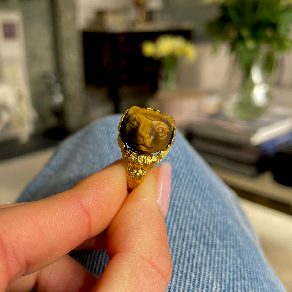 Unusual tiger's eye honey bear and yellow gold ring, held in fingers.