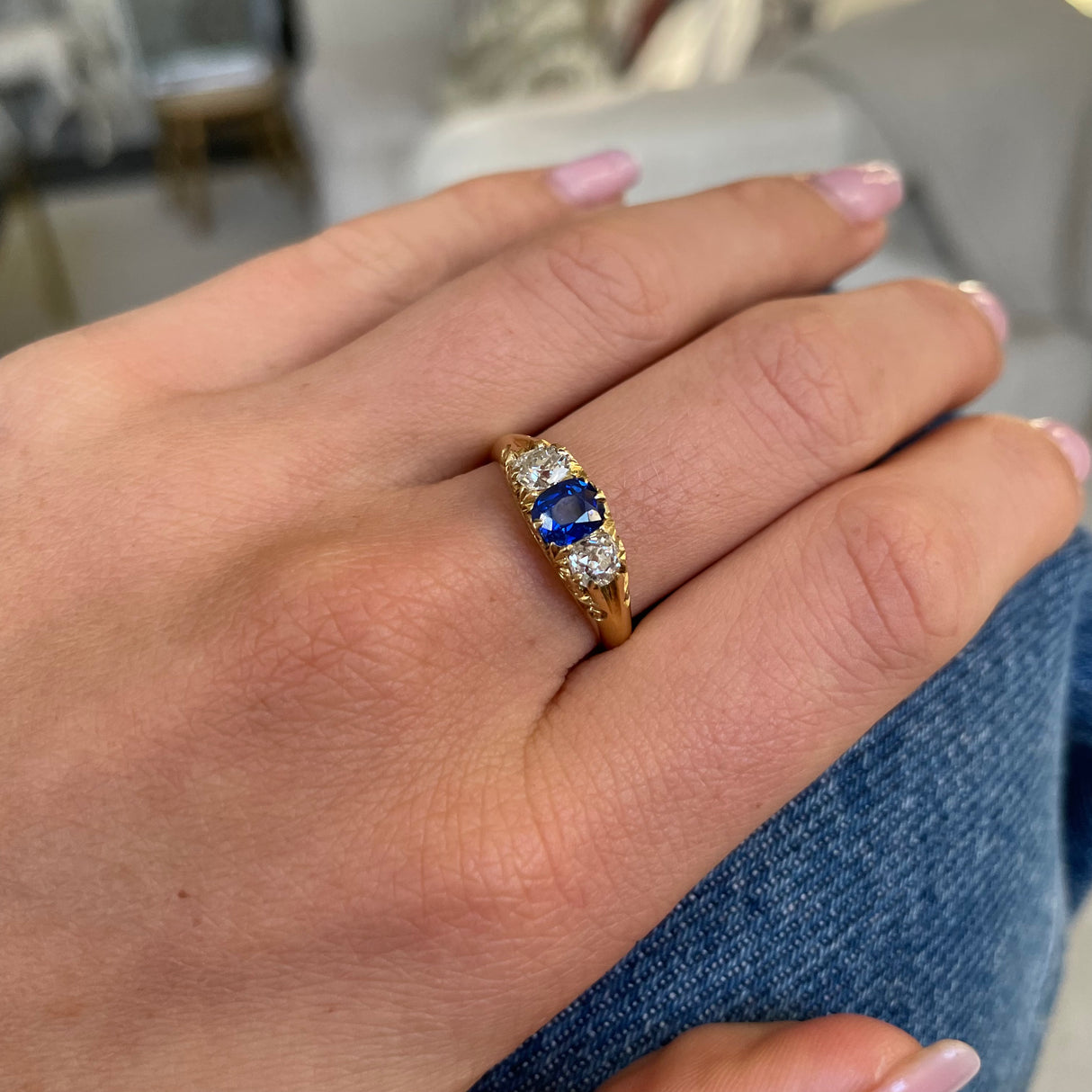 Sapphire and diamond three stone ring, worn on hand.
