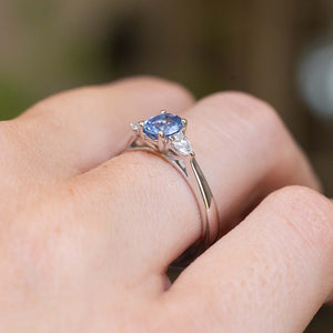 Close-up side detail of a vintage-inspired light blue sapphire and diamond three-stone engagement ring worn on the finger.