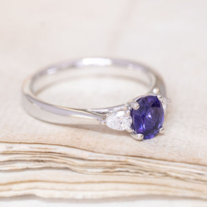 A vintage-inspired, indigo sapphire & diamond three-stone engagement ring in platinum showing the flanked diamond. 