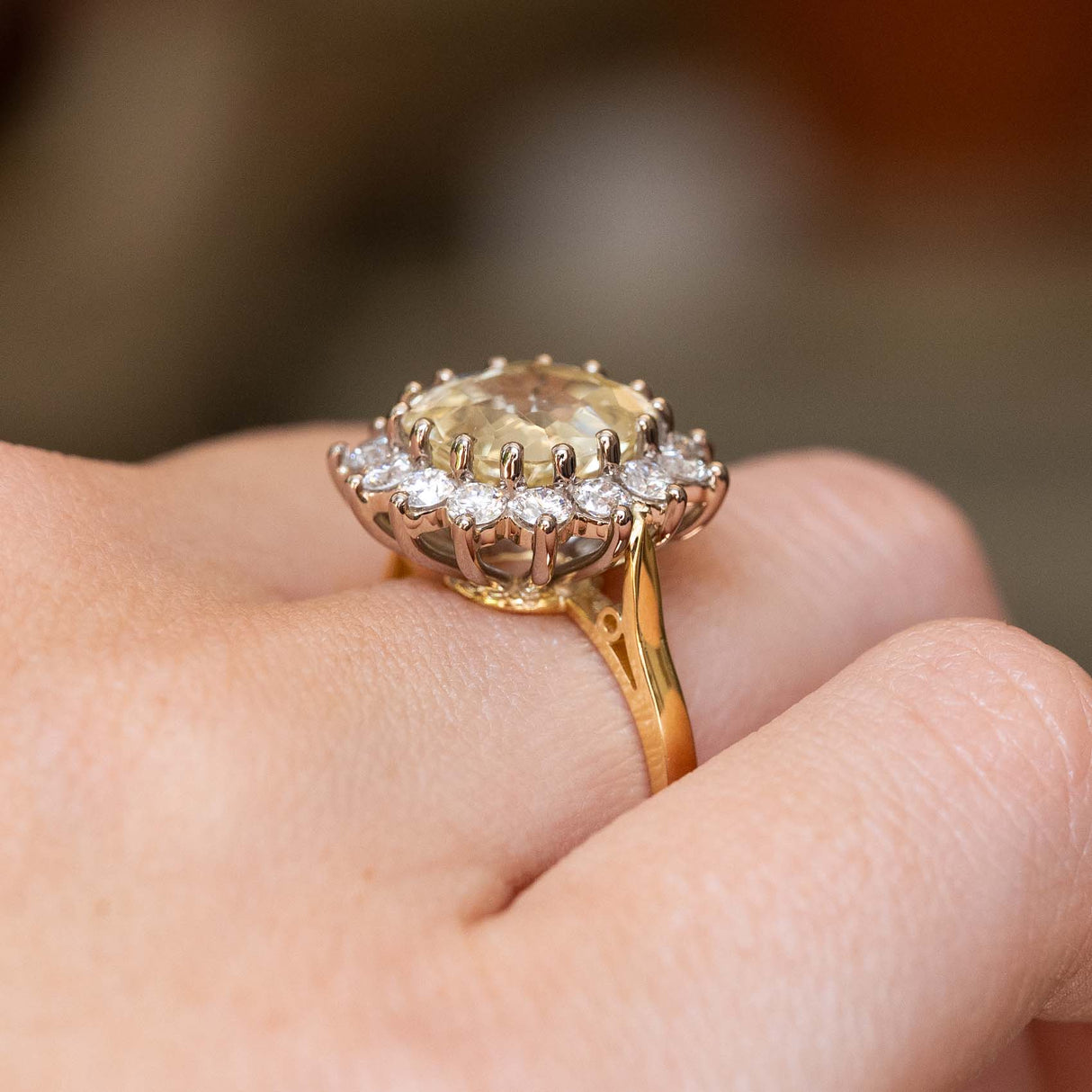 An antique-inspired, yellow Ceylon sapphire and diamond cluster engagement ring in white and yellow gold with a raised gallery.