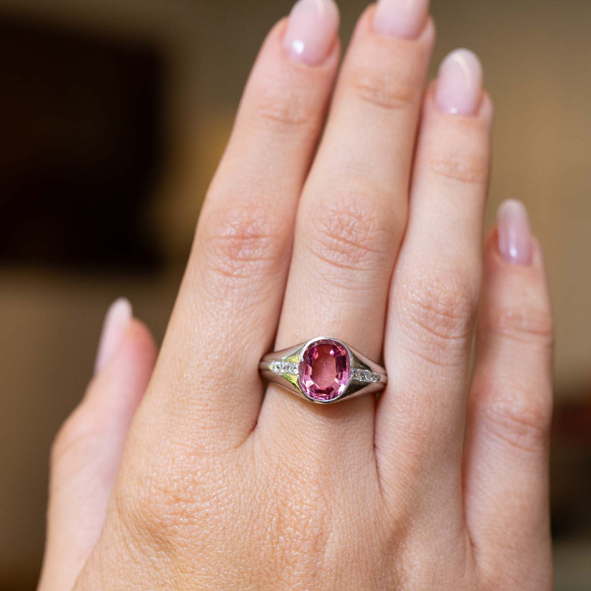 An outstretched hand wearing a Vintage, 1940s pink sapphire and diamond gypsy ring in platinum to show scale