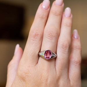 An outstretched hand wearing a Vintage, 1940s pink sapphire and diamond gypsy ring in platinum to show scale