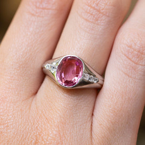 A platinum Vintage, 1940s pink sapphire and diamond gypsy ring being worn on a hand