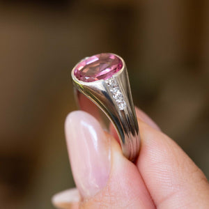 Close up detail of a hand holding a Vintage, 1940s pink sapphire and diamond gypsy ring at an angle to show the shoulders