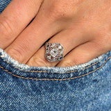 Antique Art Deco diamond and sapphire cluster ring in platinum styled on hand against blue denim, highlighting the rich blue sapphire centre stone, brilliant diamond halo and timeless 1920s design.