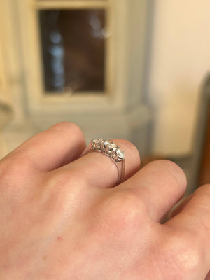 Intricate side profile of 1950s white gold diamond three stone ring worn on hand.