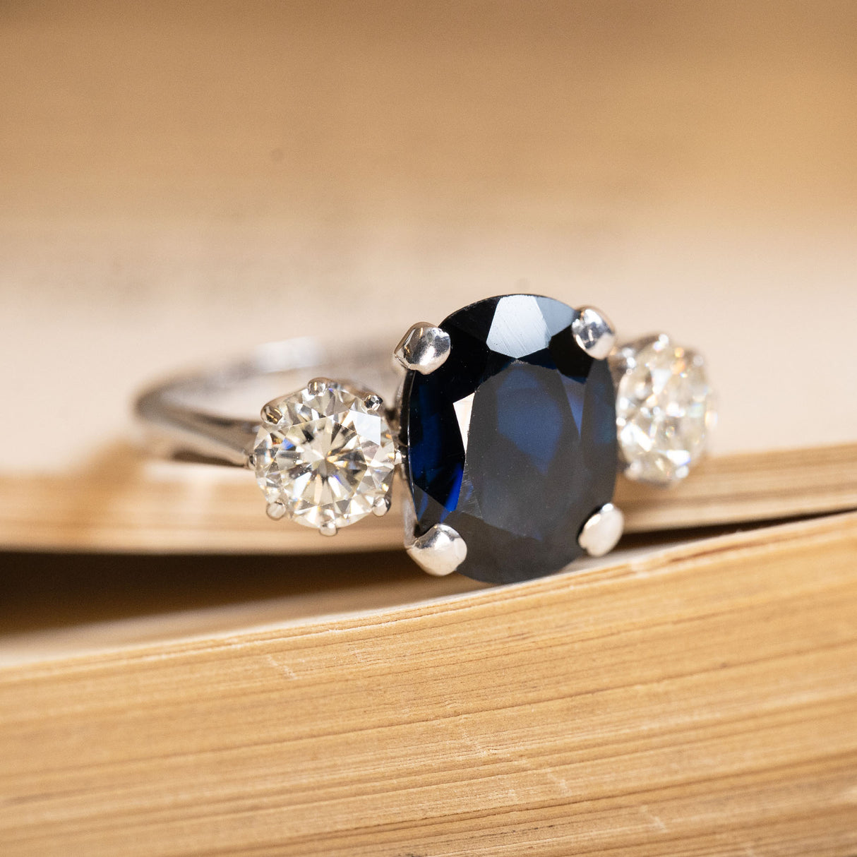 Vintage midnight-blue sapphire and diamond three-stone ring showcasing an oval sapphire centre stone with diamond side stones in a classic white gold setting.
