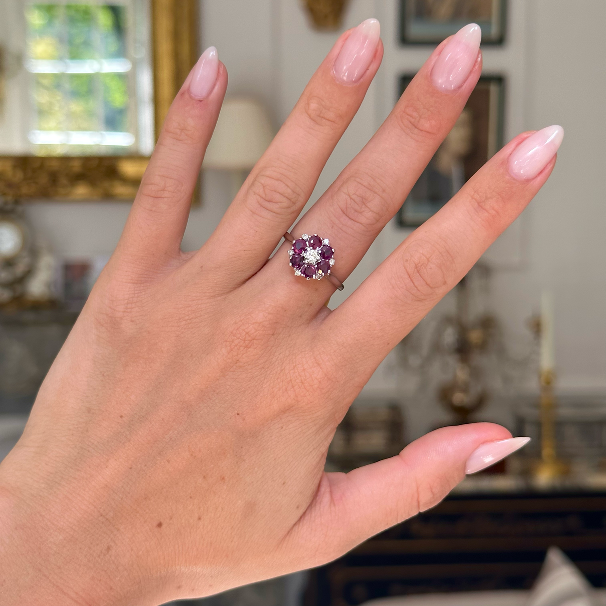 ruby and diamond cluster ring, worn on hand front view. 