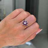 ruby and diamond cluster ring worn on closed hand, front view. 