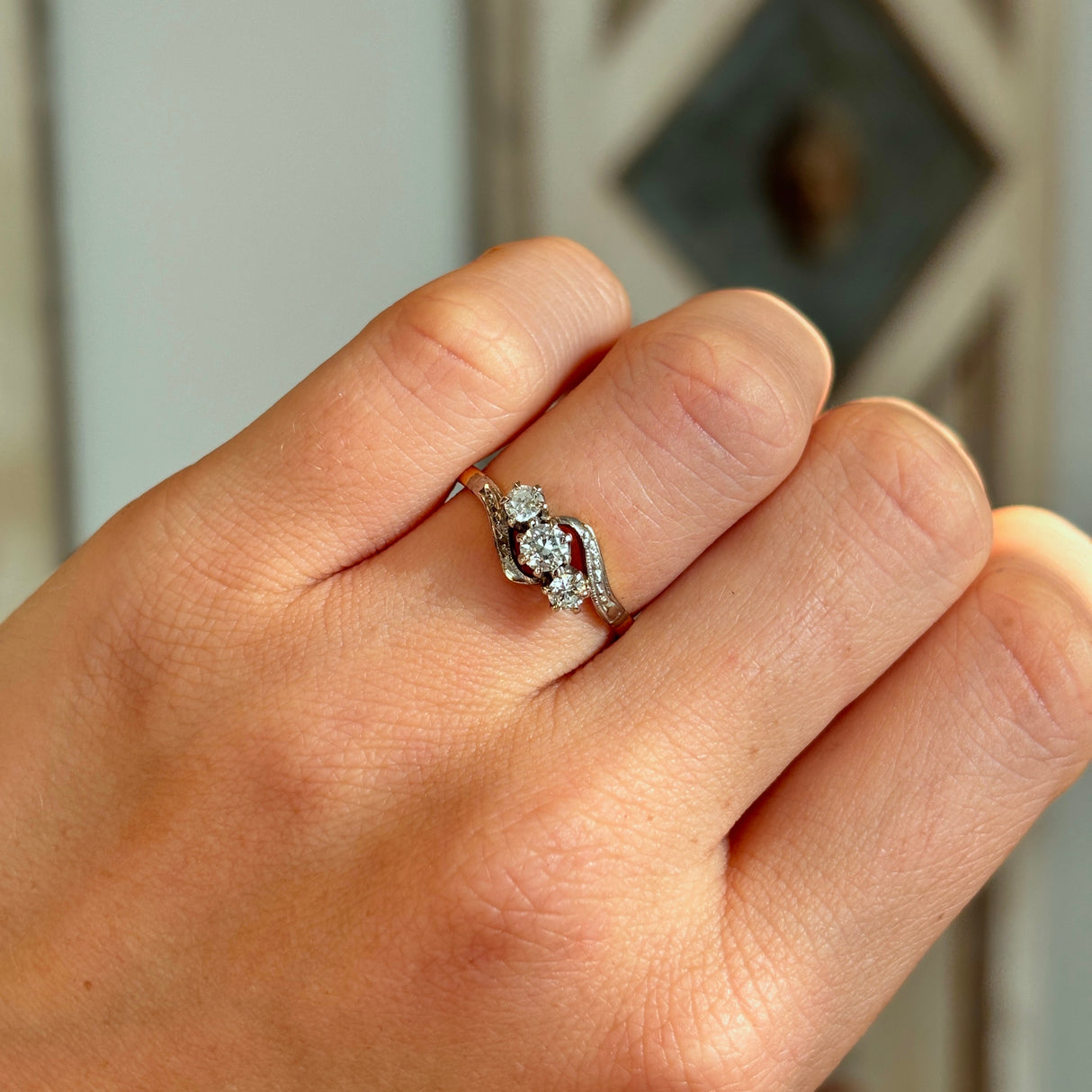 Antique, Edwardian three-stone diamond twist ring worn on hand.