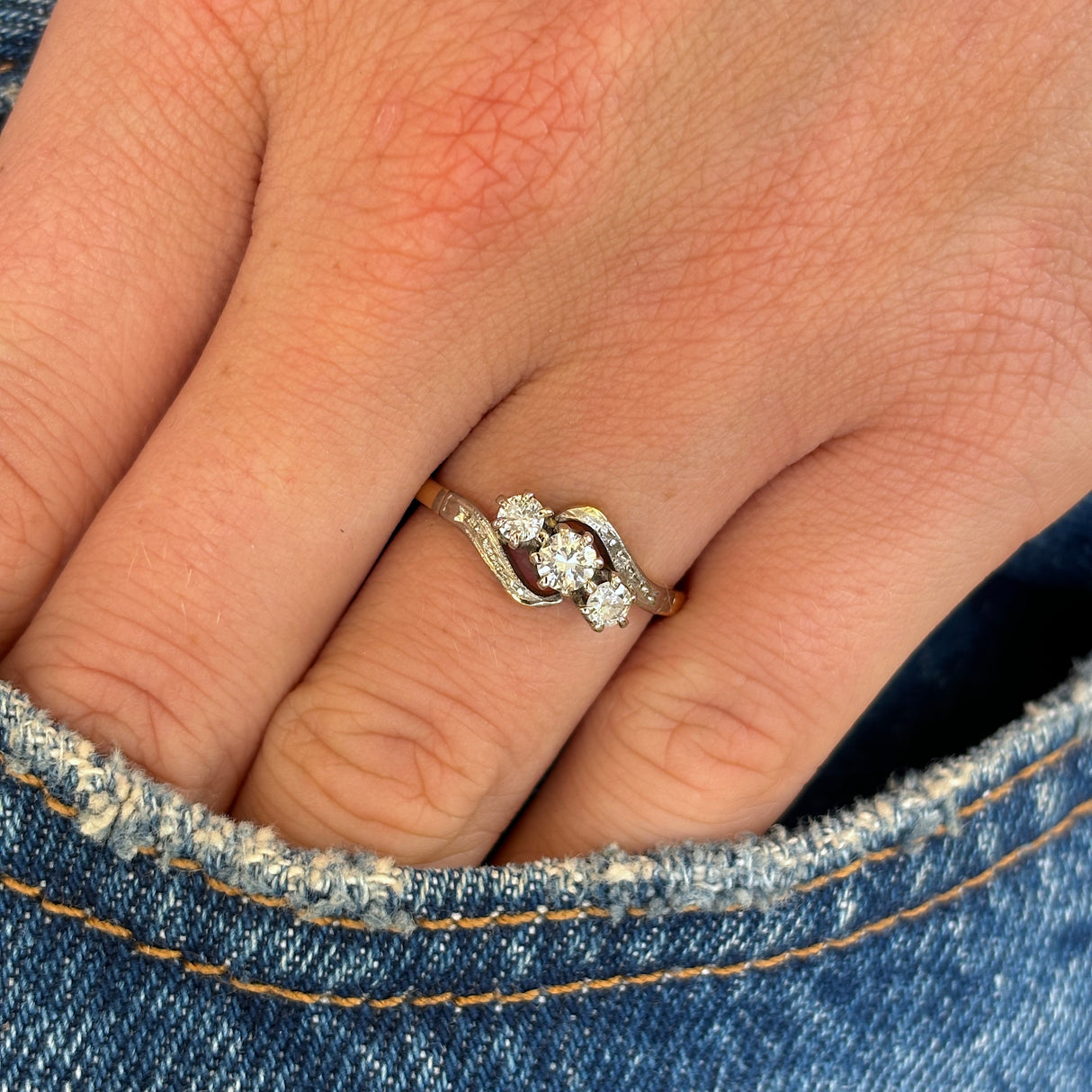 Antique, Edwardian three-stone diamond twist ring worn on hand.