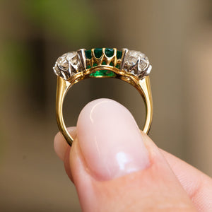 Rear view of an antique Edwardian octagon-cut emerald and old-mine diamond three-stone engagement ring in yellow gold.