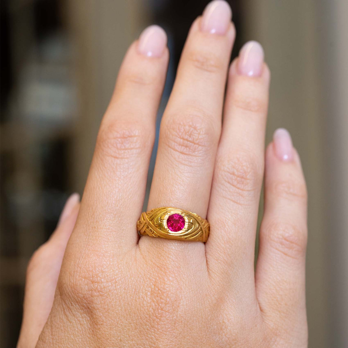 A hand outstretched wearing an Antique, Art Nouveau ruby single-stone yellow gold gypsy ring