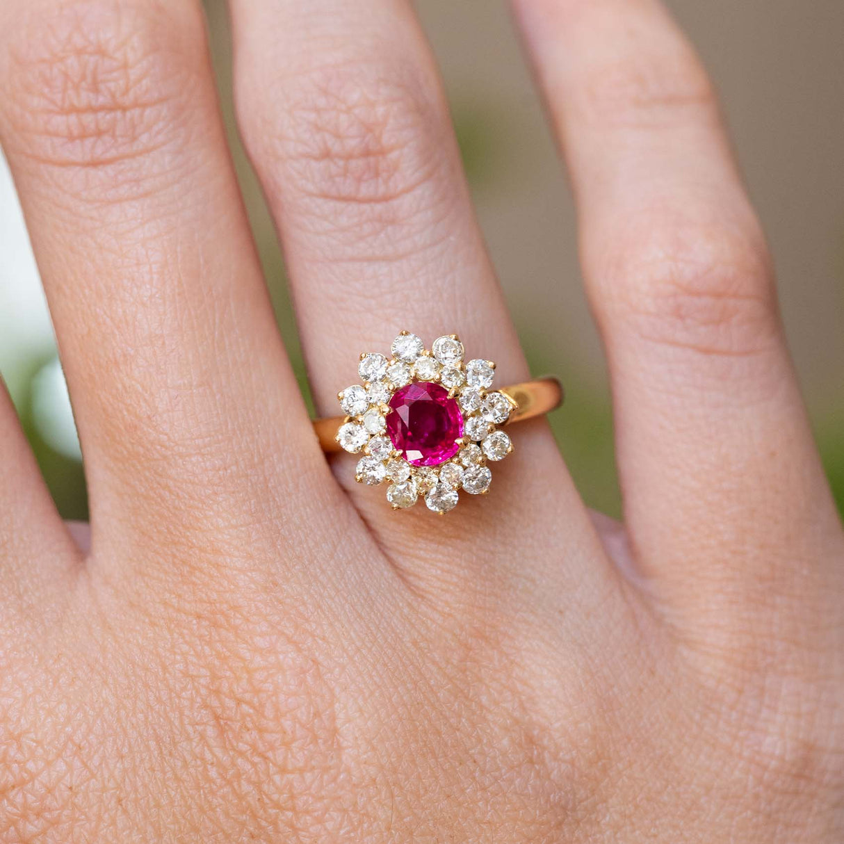 A vintage 1980s Burmese ruby and diamond cluster ring worn on the finger.