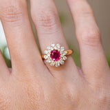 A vintage 1980s Burmese ruby and diamond cluster ring worn on the finger.