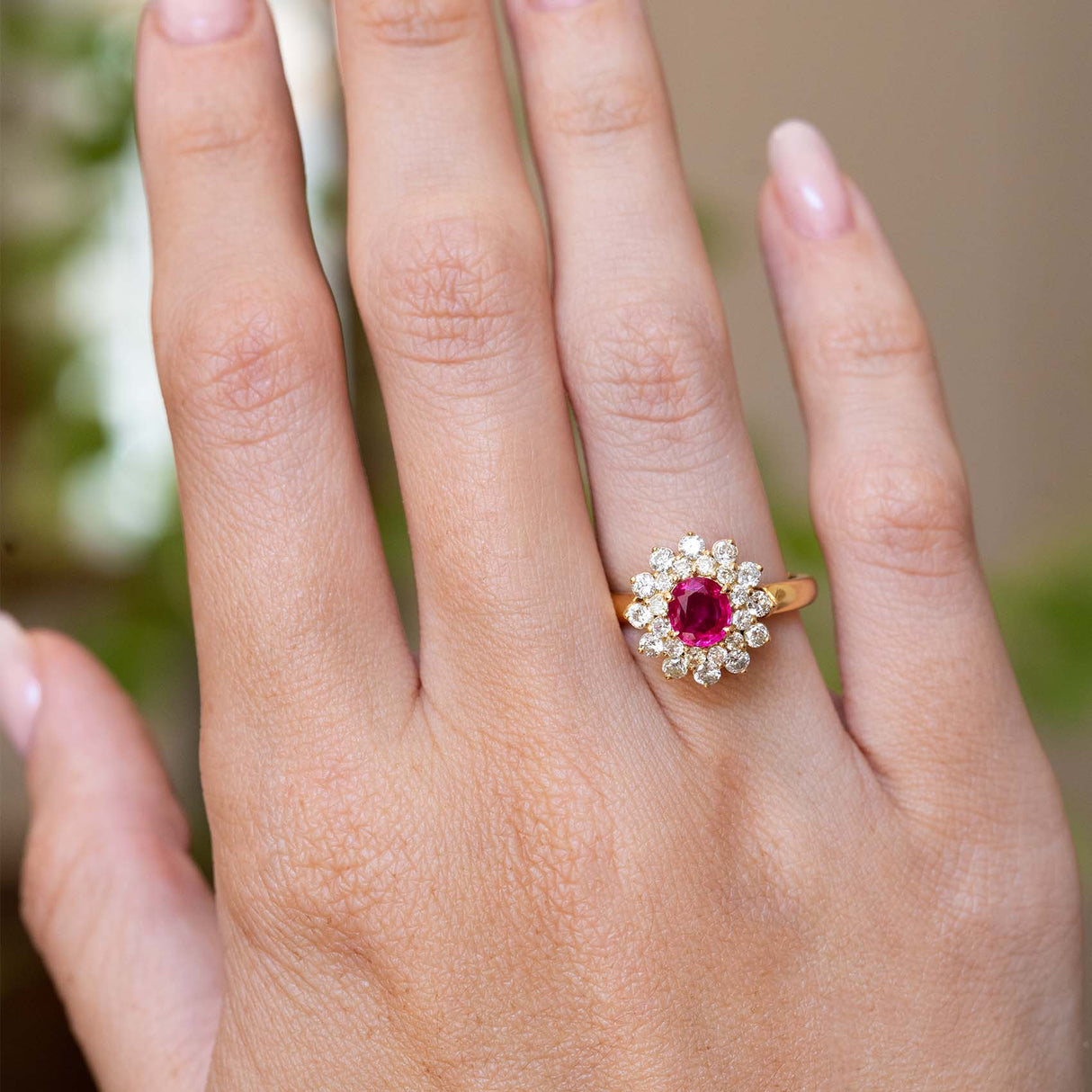 A vintage 1980s Burmese ruby and diamond cluster ring worn on the hand.