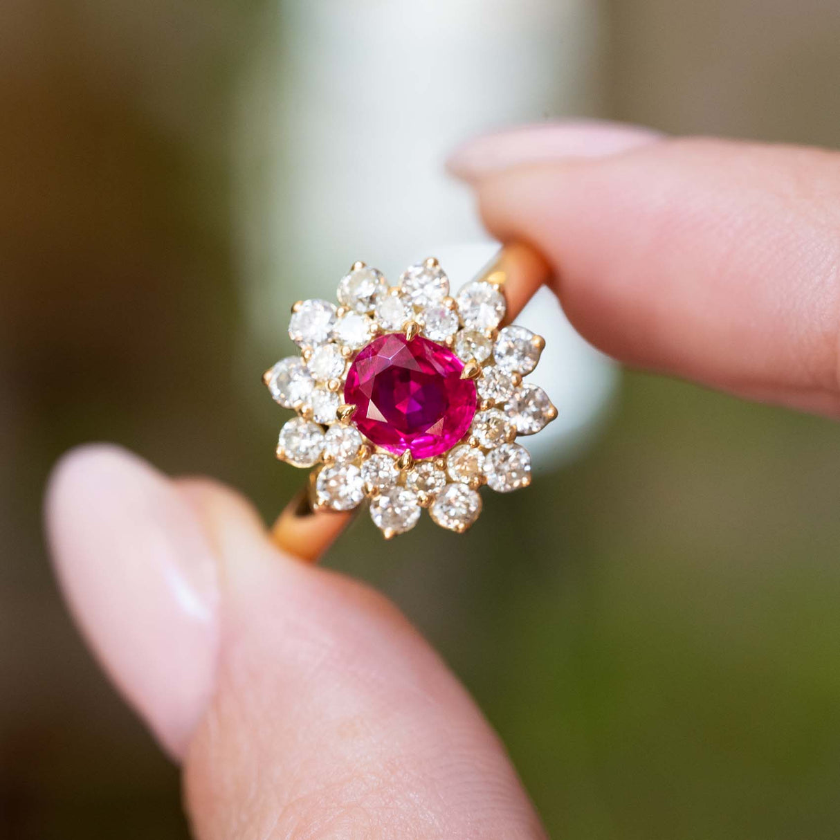 A close-up of a vintage 1980s Burmese ruby and diamond cluster ring in yellow gold.