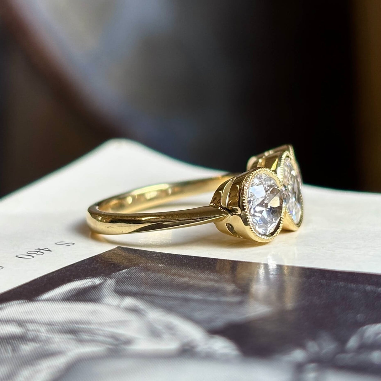 Antique, Victorian three-stone diamond ring shot on a vintage book with a blurred background