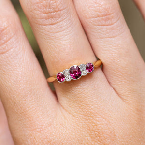 An antique Edwardian ruby and diamond five-stone engagement ring worn on the finger.