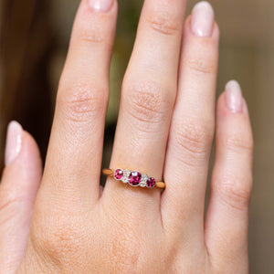 Edwardian ruby and diamond five-stone engagement ring displayed on the hand.