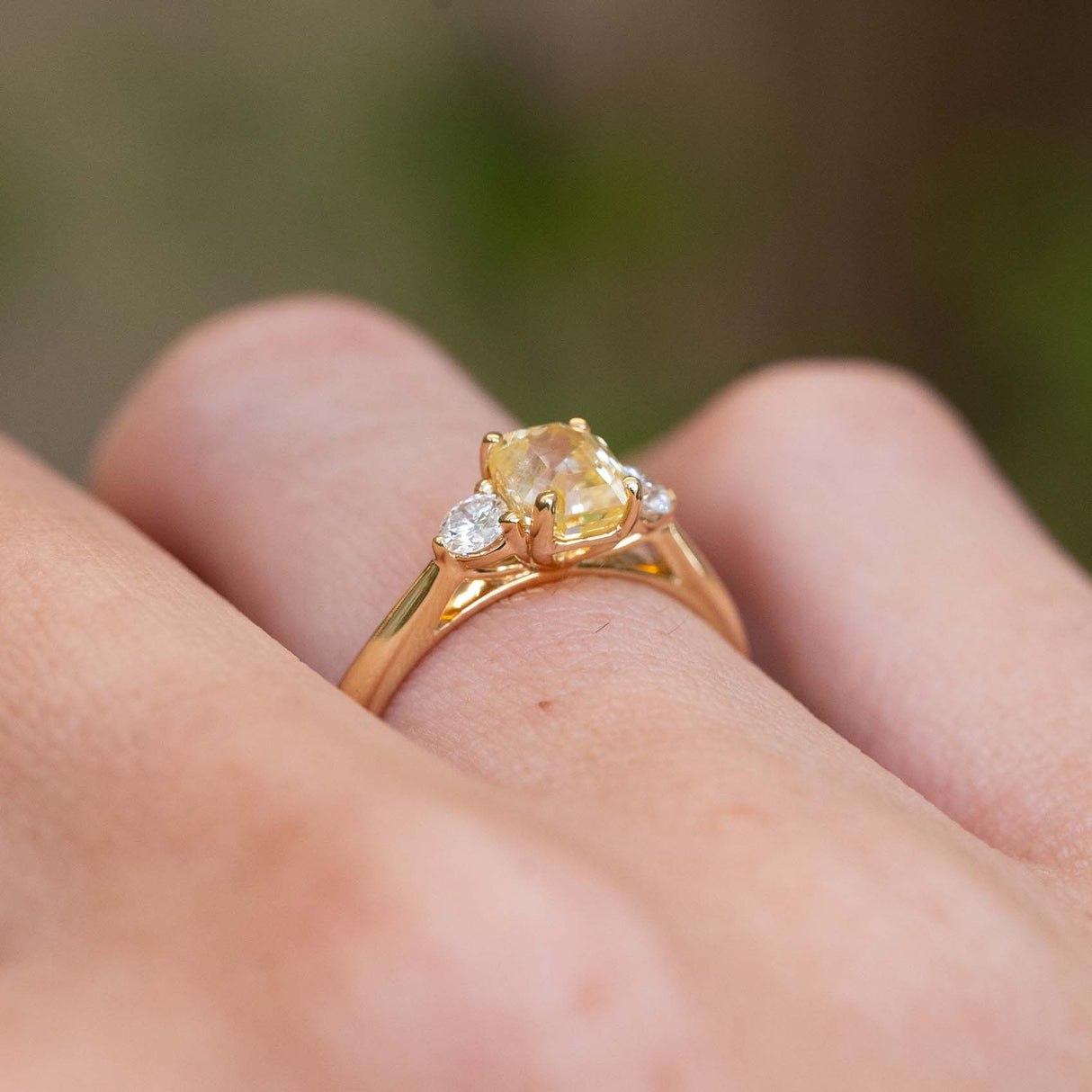 A side view of a vintage-inspired yellow sapphire and diamond three-stone ring in yellow gold.