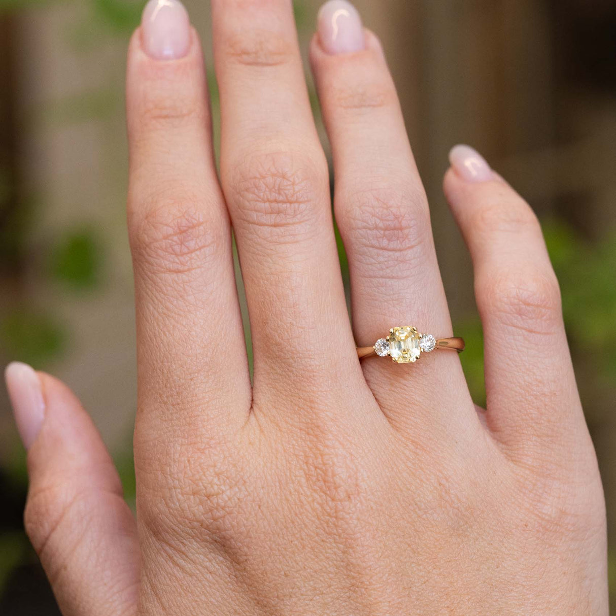 A vintage-inspired yellow sapphire and diamond engagement ring worn on the hand.