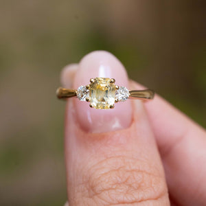 Close detail of a vintage-inspired yellow sapphire and diamond three-stone ring in yellow gold.