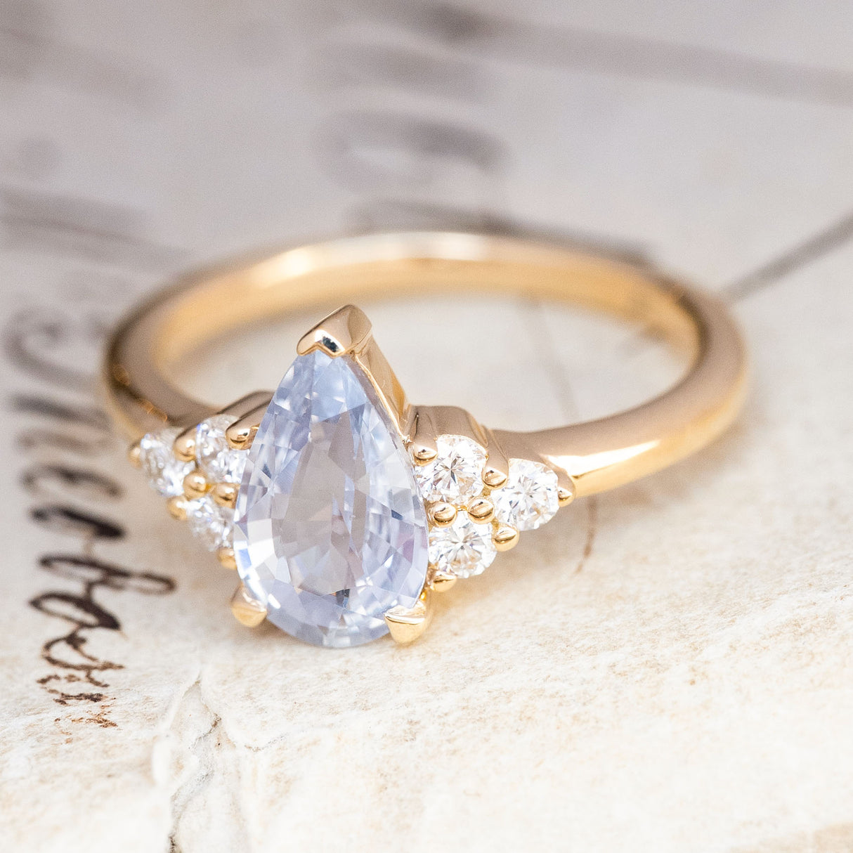An antique-inspired White-blue sapphire and diamond cluster tre-foil engagement ring.
