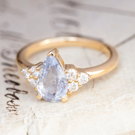 An antique-inspired White-blue sapphire and diamond cluster tre-foil engagement ring.