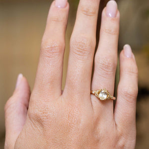 Oval-cut yellow sapphire and diamond engagement ring displayed on the hand in a yellow gold setting.