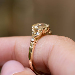 Side detail of an antique-inspired oval-cut yellow sapphire and diamond engagement ring in yellow gold.