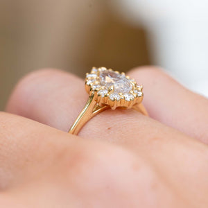 Side profile of a vintage-inspired white sapphire and diamond halo engagement ring in yellow gold.