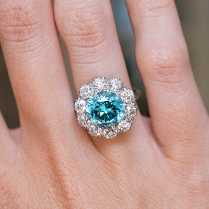 An antique Edwardian zircon and diamond cluster cocktail ring worn on the finger.