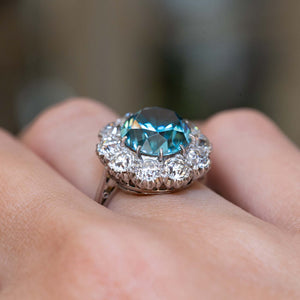 Side view of an antique Edwardian zircon and diamond cluster cocktail ring worn on the finger.