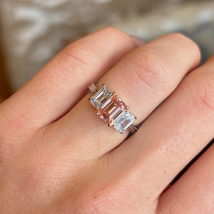 Lab-pink diamond and white diamond three-stone ring worn on the engagement ring finger, exhibiting the brilliance and presence when worn.