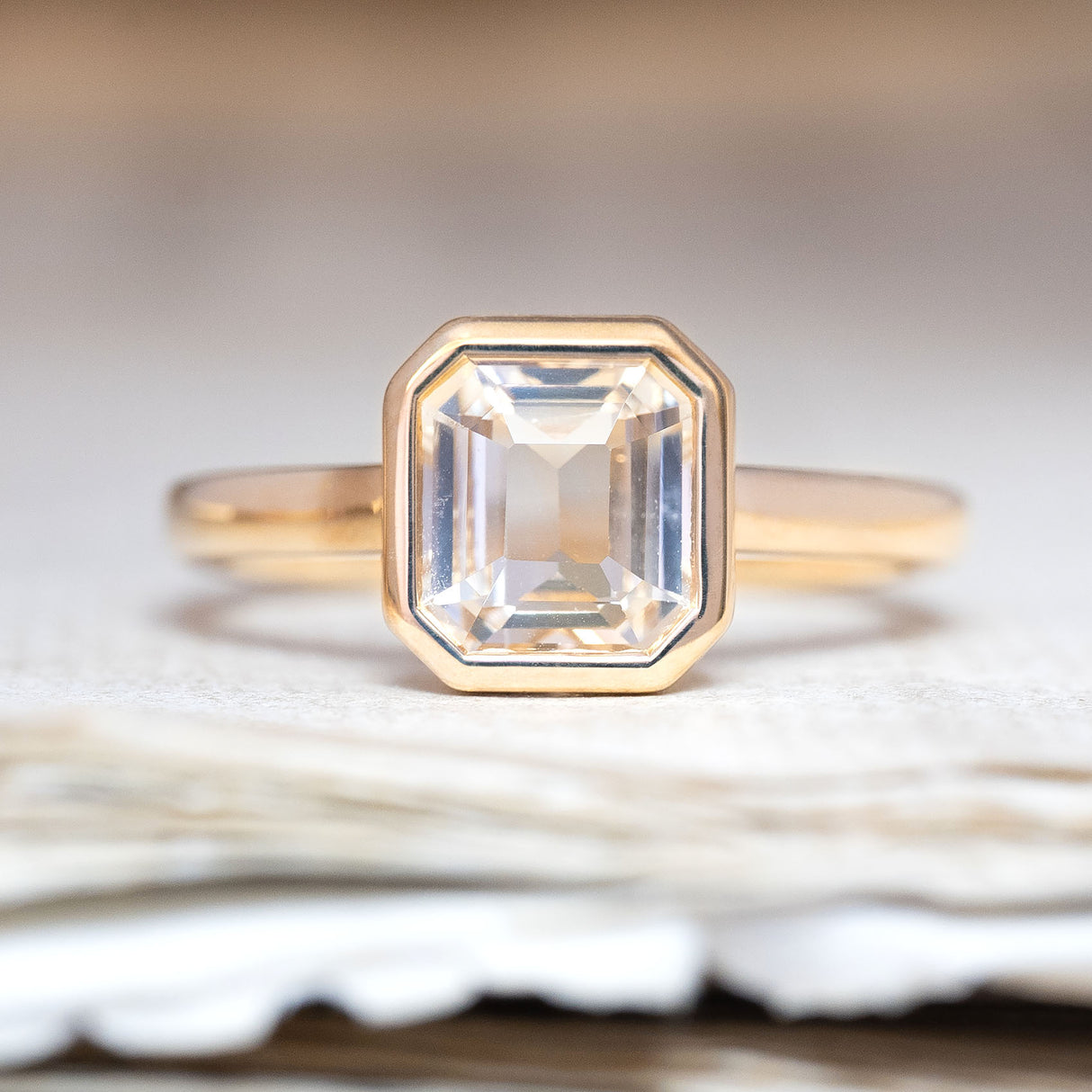 An antique-inspired, pale yellow sapphire solitaire engagement ring in yellow gold.