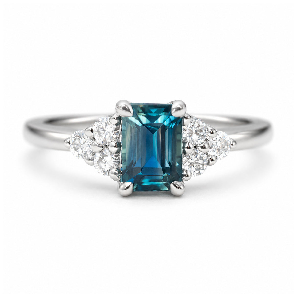 A close-up photo of a vintage-inspired, blue-green sapphire and diamond cluster trefoil engagement ring in platinum.