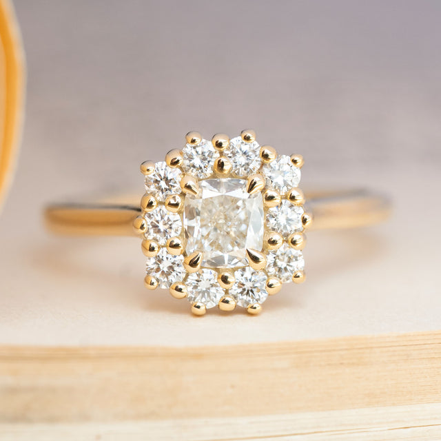 Antique-inspired cushion-cut diamond halo engagement ring in yellow gold.