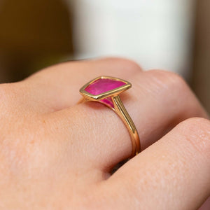 A vintage-inspired, pink ruby solitaire engagement ring showing the minimalistic rub-over setting.
