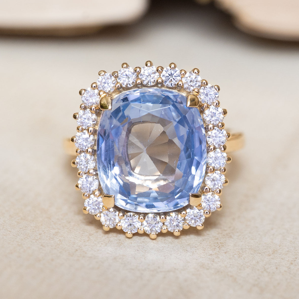 An antique-inspired cornflower blue sapphire and diamond cluster ring in yellow gold.