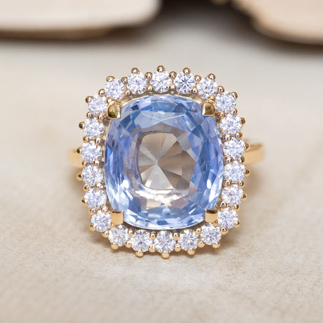 An antique-inspired cornflower blue sapphire and diamond cluster ring in yellow gold.