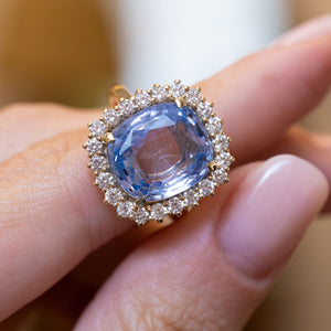 Close-up of an antique-inspired soft blue sapphire and diamond cluster ring in yellow gold.