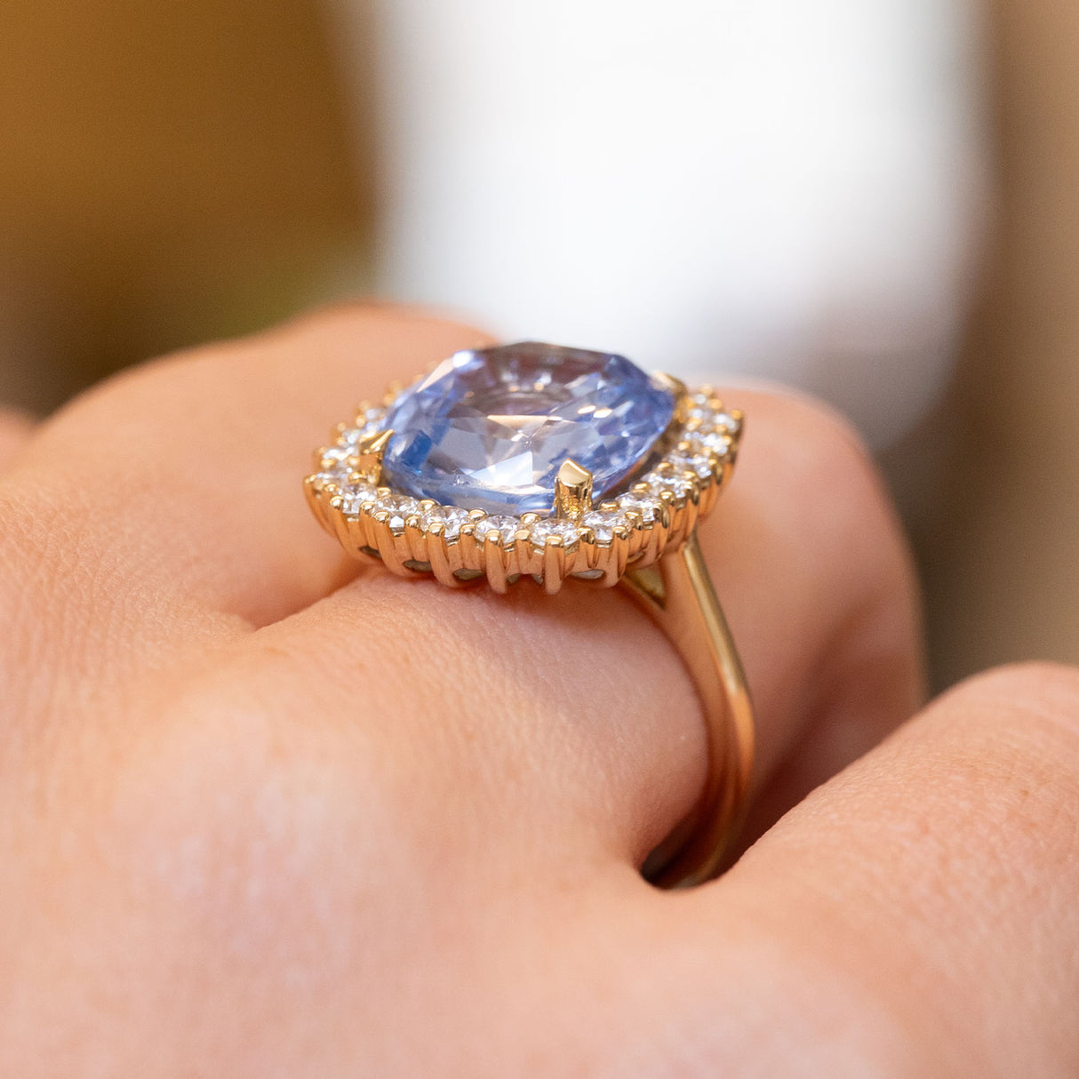 Side view of a vintage-inspired soft blue sapphire and diamond cluster ring in yellow gold showing the gallery