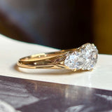 Antique Victorian three-stone with cushion-cut and pear-cut diamonds ring on a vintage book with a blurred background
